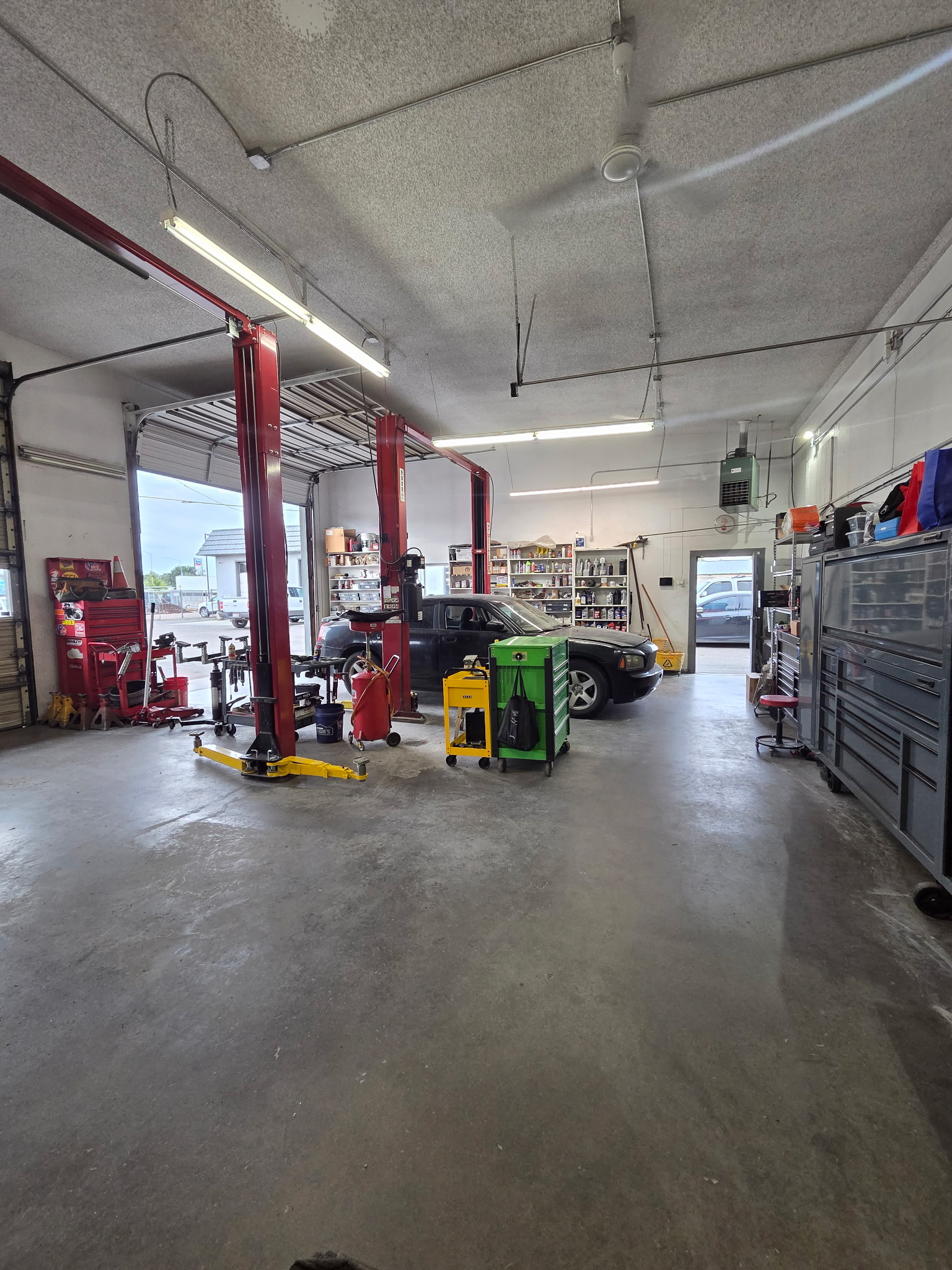 Original DeMark Auto workshop photograph with vehicle lifts, tools and a pickup